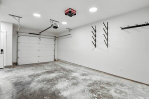A garage with a white door, ceiling lights, a projector, and wall-mounted hooks. - Ridgeline | Slope-Side | Hot Tub | Resort Access (Panorama)