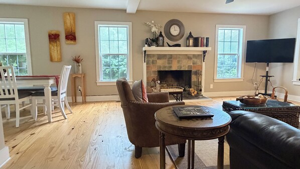 A living room with a fireplace, a dining area with a table and chairs, and a television.