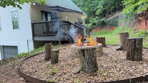Ein Haus mit einer Terrasse, einem Feuerkorb und einem Steinkreis für Feuer.