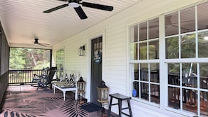 A covered porch with a ceiling fan, a bench, a table, and a lantern.