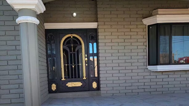 Un ingresso di un edificio con una porta nera, colonne bianche e una finestra.