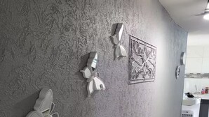Una parete strutturata con decorazioni e un punto elettrico, con uno scorcio della cucina.