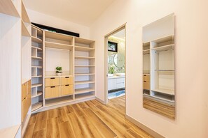 Un vestidor amplio con estantes y cajones, una planta pequeña y un espejo.