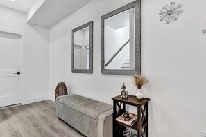 A hallway with a bench, a door, and two wall-mounted mirrors. - Dallas Escape w/ Rooftop + Yard • Sleeps 10 (Dallas)