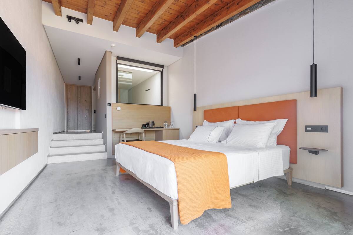 A modern bedroom with a bed, a desk, and a mirror.