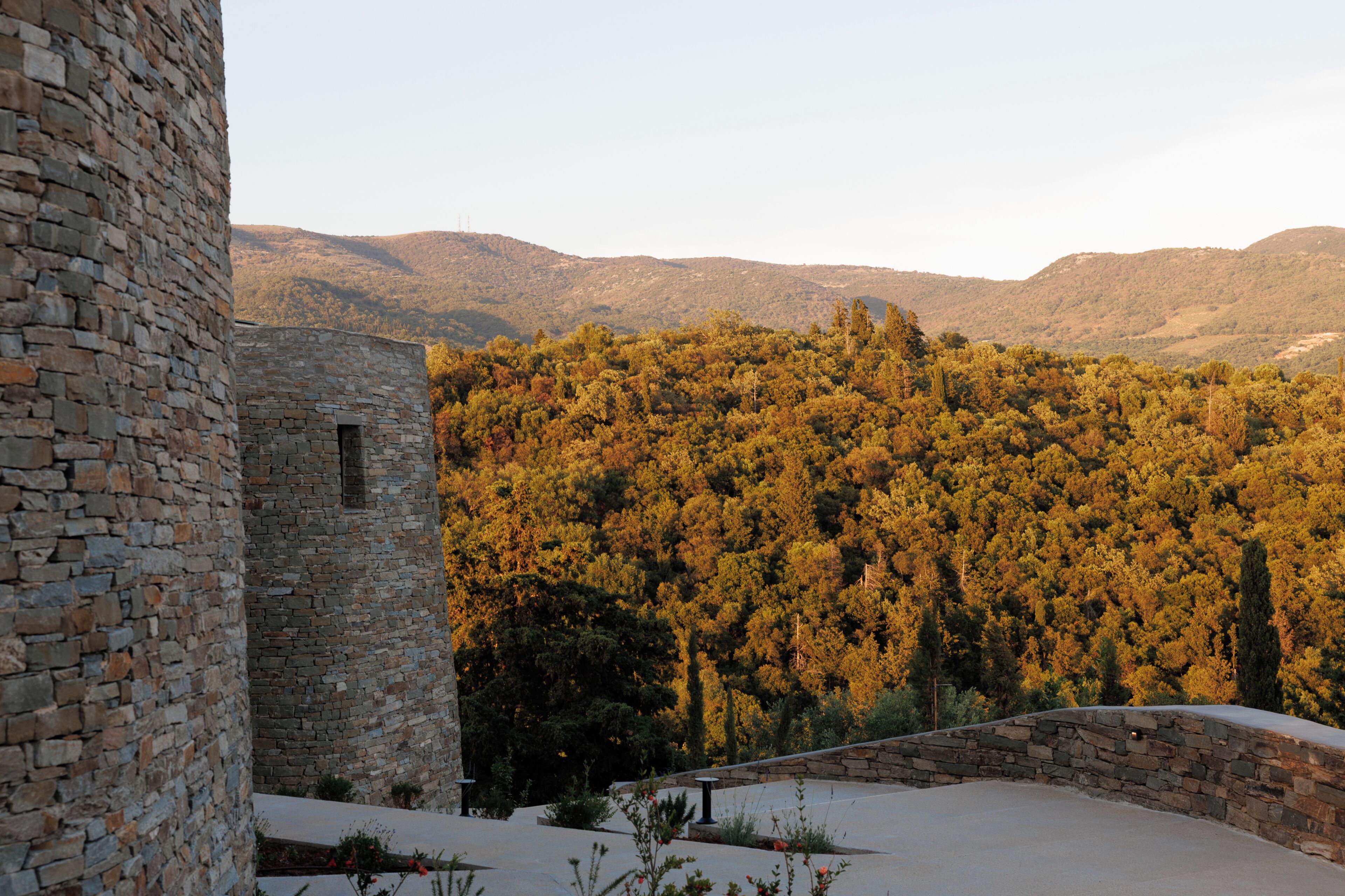 A stone building with a view of a forested hillside.