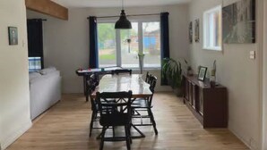 En matplats med ett långt bord och stolar, en hängande lampa och utsikt genom ett fönster.
