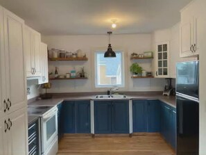 A kitchen with white cabinets, a black pendant light, and a window.