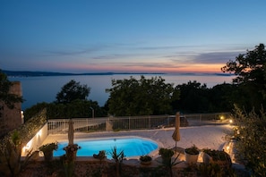 A swimming pool with a view of the sea and hills at dusk. - Villa Ole | Mediterranean Stone Villa with Pool, Jacuzzi (Jesenice)