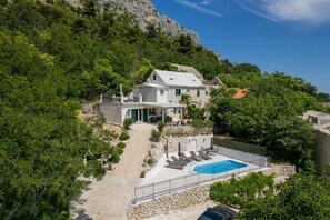 A hillside villa with a swimming pool, outdoor seating, and a stone staircase. - Villa Ole | Mediterranean Stone Villa with Pool, Jacuzzi (Jesenice)
