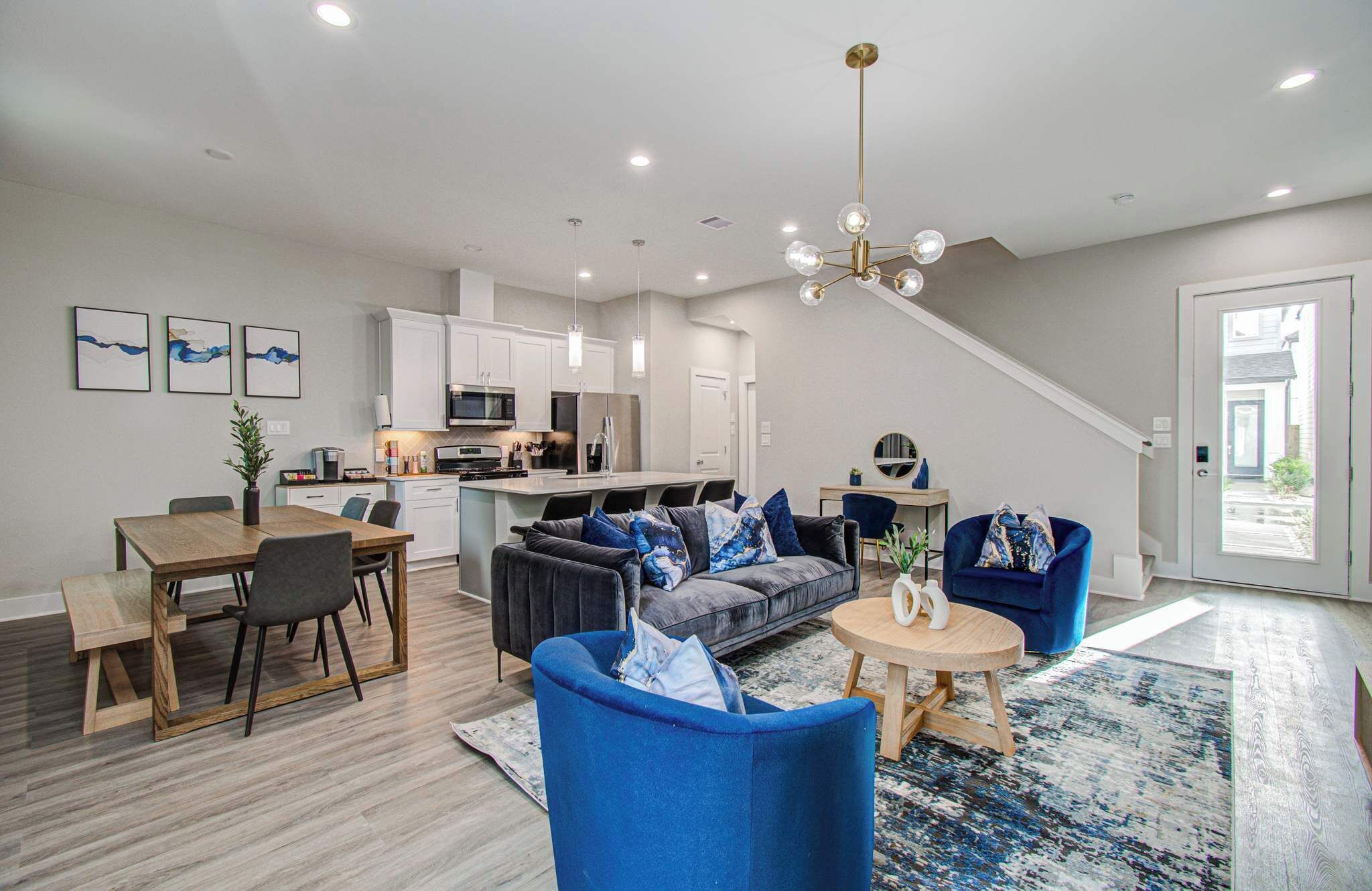 A modern living room with a sofa, chairs, a coffee table, and a dining area with a table and chairs.