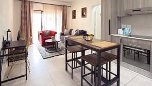 Un soggiorno moderno con tavolo da pranzo, divano rosso e angolo cucina.