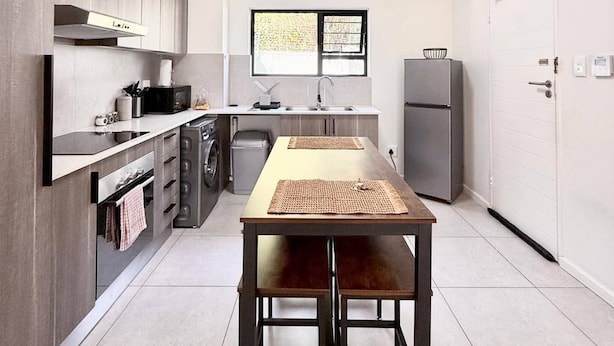 Una cucina moderna con tavolo da pranzo, elettrodomestici integrati e una finestra.