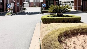 Un edificio con un cartello che riporta 'The Aurora' e un ingresso coperto. Si notano cartelli direzionali, un segnale di stop e un segnale 3T.
