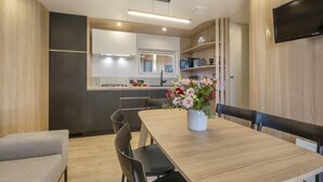 Eine moderne Küche mit Essbereich, einem Flachbildfernseher und einem Blumenstrauß auf dem Tisch.