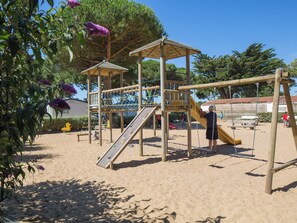 Un parque infantil con tobogán, red de escalada y columpios.