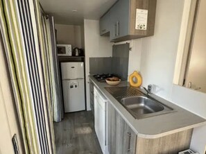 Eine kleine Küche mit Mikrowelle, Kühlschrank, Spüle und einer Arbeitsplatte.