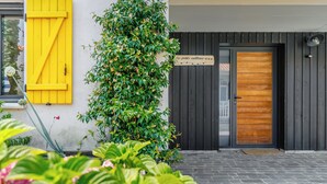 Un edificio moderno con una porta in legno, un battente giallo e un cartello che riporta la scritta 'Les petits cailloux'.