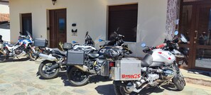 A row of motorcycles parked outside a building with a tiled entrance. - Theofania's Marble House Meteora (Kastraki)