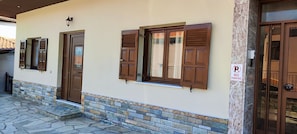 A building with a stone facade, wooden doors, and shutters. - Theofania's Marble House Meteora (Kastraki)