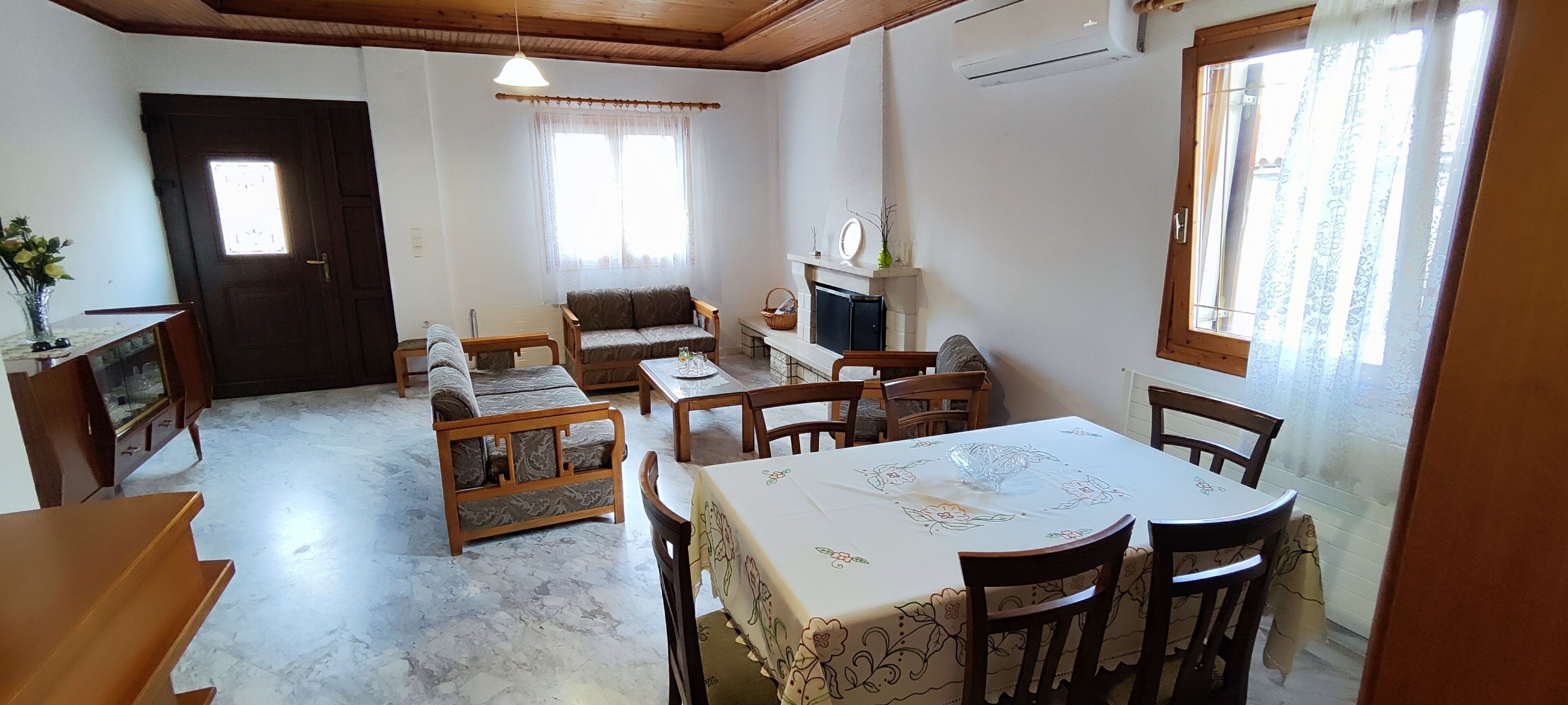 Ein gemütliches Wohnzimmer mit Sofa, Sesseln, einem Esstisch und einem Kamin.