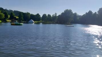 A calm lake with boats, a dock, and a forested hill in the background.
