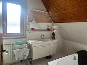 Ett badrum med ett fönster, ett handfat, en spegel, en handdukshängare och en toalett.