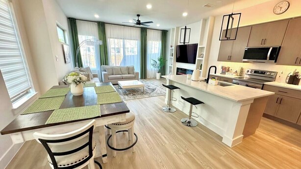 Eine moderne Küche mit Essbereich, Holzboden und Deckenventilator.