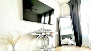 Ein modernes Zimmer mit einem Flachbildfernseher, einem dekorativen Spiegel und einem stilvollen Konsolentisch.