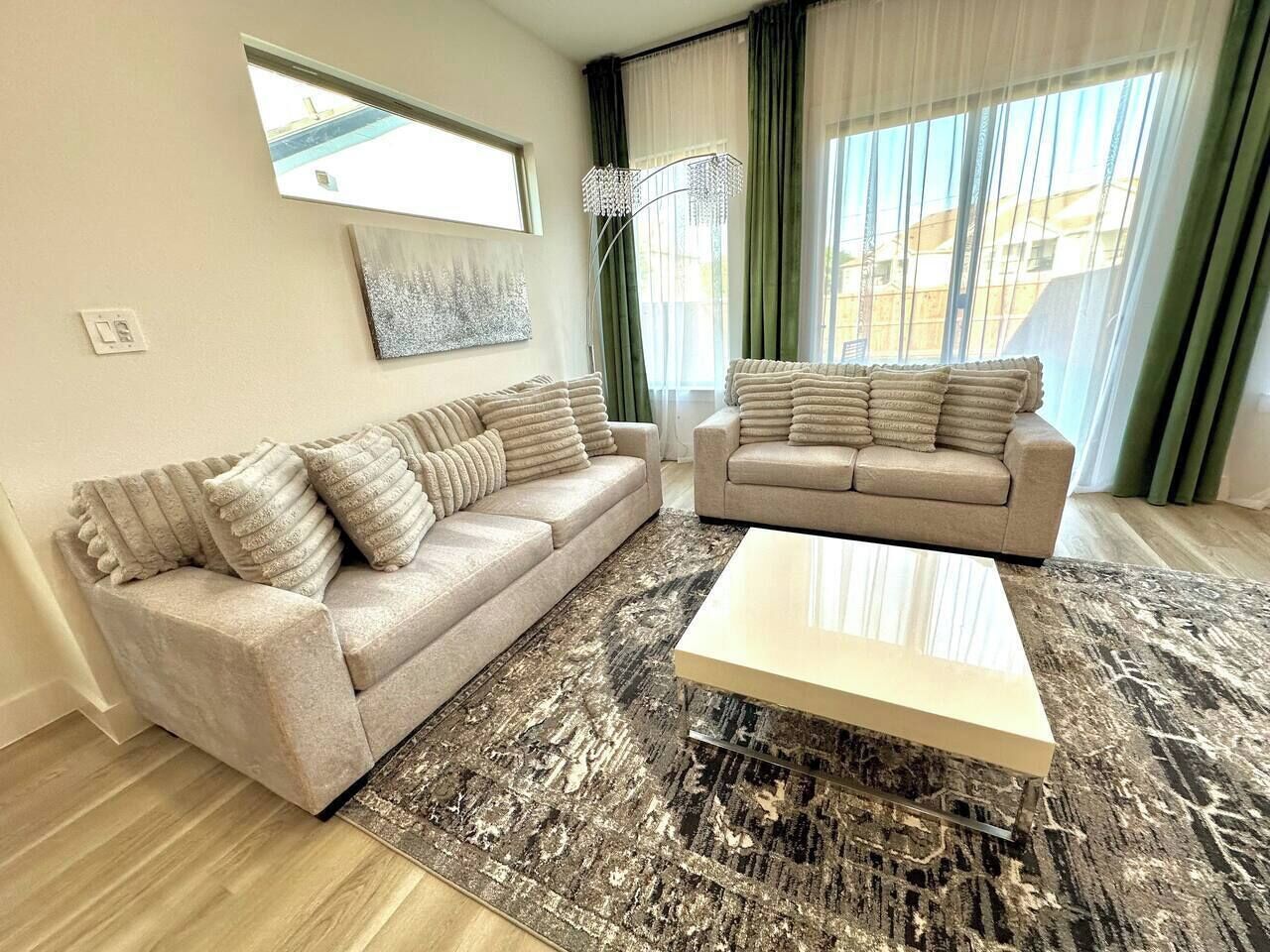 Un salon avec deux canapés, une table basse, un tapis à motifs et une fenêtre avec des rideaux.