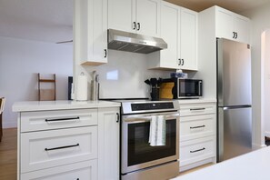 Une cuisine moderne avec des meubles blancs, des appareils en acier inoxydable et un four à micro-ondes posé sur le plan de travail.