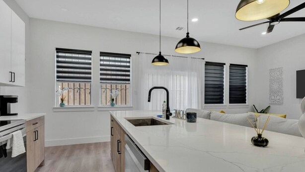 Cozinha moderna com uma ilha grande, luminárias pendentes e um ventilador de teto.