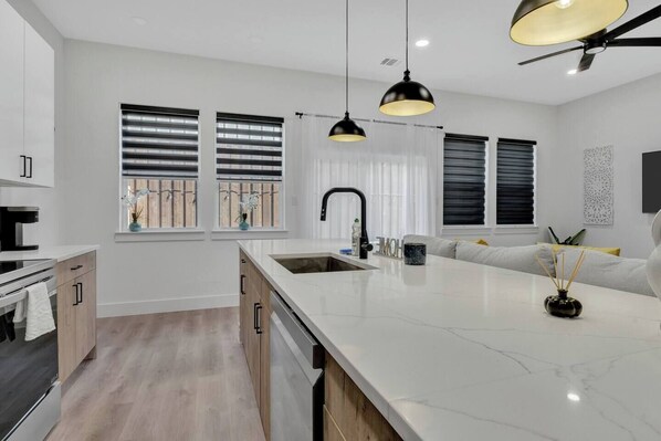 A modern kitchen with a large island, pendant lighting, and a ceiling fan. - Bright Dallas 3BR | Rooftop, Garage, Backyard - Holiday Home (Dallas)