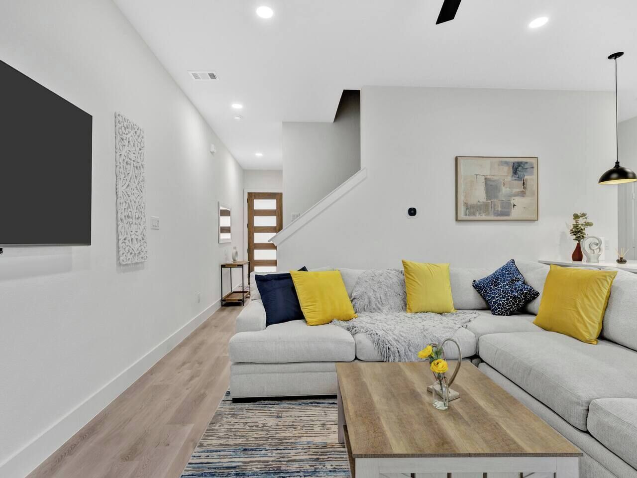 A modern living room with a sectional sofa, a coffee table, and a staircase.