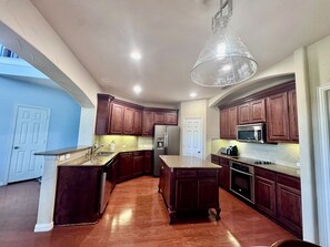 A modern kitchen with wooden cabinets, stainless steel appliances, and a large island. - Near FIFA World Cup Dallas Stadium, Golf view home (Grand Prairie)