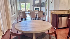 A dining area with a round table, four chairs, a chandelier, a kitchen with a dishwasher, and a view of the outdoors. - Near FIFA World Cup Dallas Stadium, Golf view home (Grand Prairie)