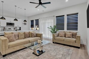 Ein modernes Wohnzimmer mit zwei Sofas, einem Glastisch und einem Deckenventilator.