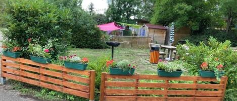 A wooden fence with planters, a small shed, and a bench in a garden setting.