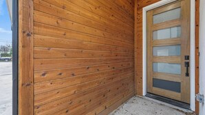 Een hoek van een gebouw met houten lambrisering en een glazen deur.