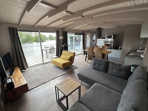 Ein modernes Wohnzimmer mit einer Couch, einem gelben Sessel und einem Essbereich mit Tisch und Stühlen.