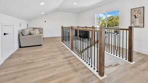 A spacious room with a wooden staircase, a sofa, and a door. - Fresh Modern 3BR • Rooftop • 5 min to Downtown (Dallas)