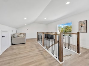 Ein geräumiges Zimmer mit einer Holztreppe, einem Sofa und einer Tür.