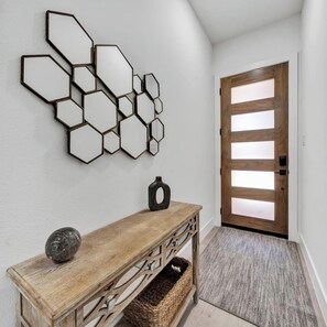 Ein Flur mit einer Holztische und einer Wand aus sechseckigen Spiegeln sowie einer Holztür.