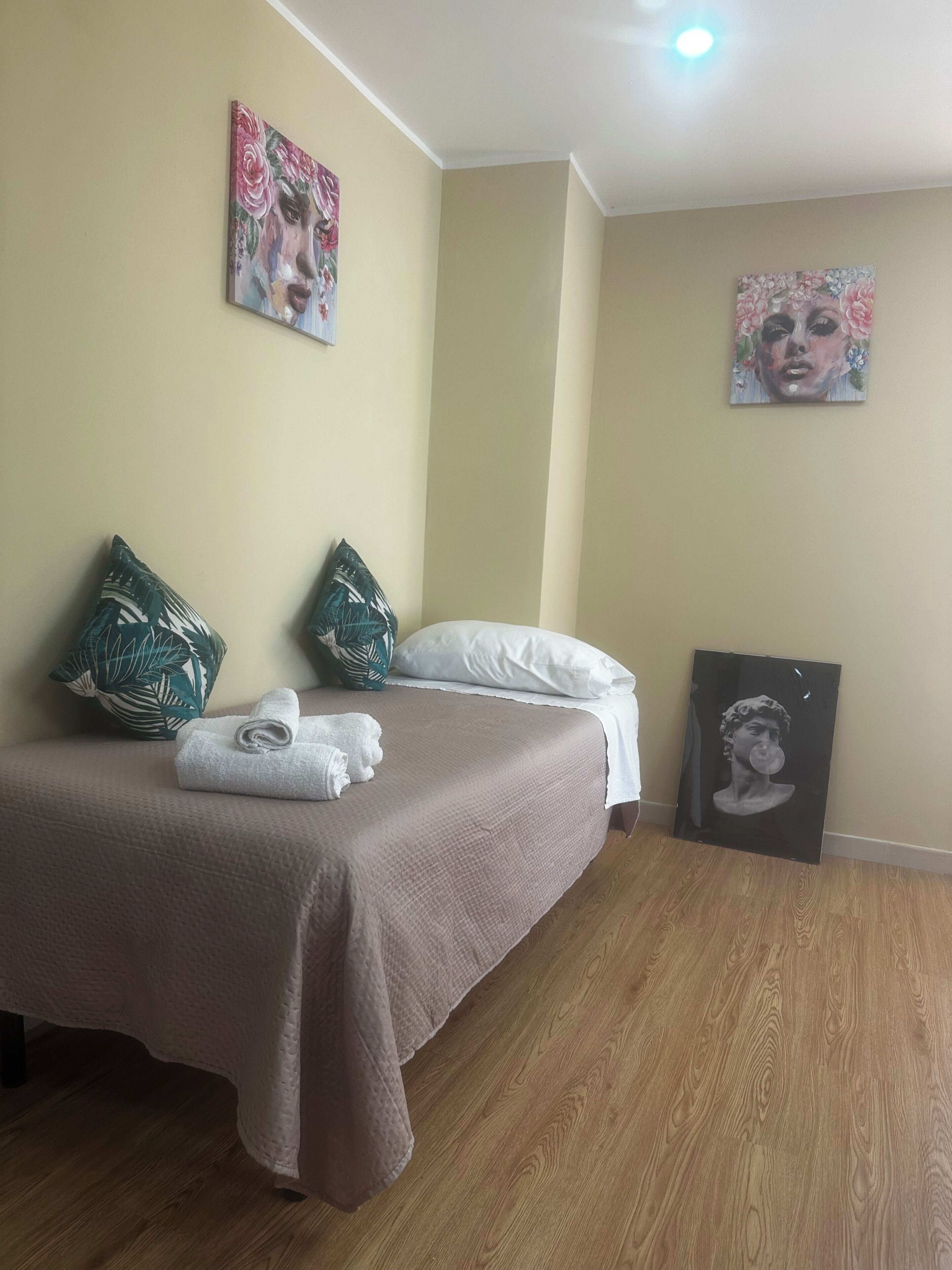 Ein Schlafzimmer mit einem Bett, Kissen, einem Gemälde und einem gerahmten Bild.