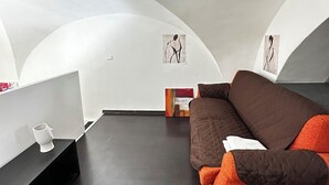 A modern interior with a curved ceiling, a brown sofa, a black table, and abstract wall art. - Spàzio apartments Duomo I (Catania)