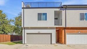 Ein zweistöckiges Wohnhaus mit Garage, Balkon und einer kleinen, abgeschlossenen Veranda.