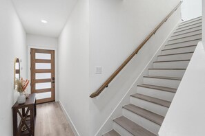 A staircase with wooden handrails and a white wall. - Modern 3BR Home w/ Rooftop • 5 min to Downtown (Dallas)