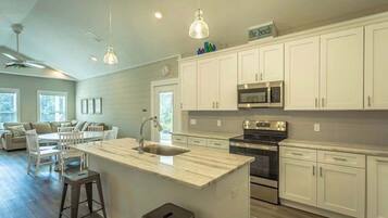 A modern kitchen with white cabinets, a central island, a microwave, and a stove.