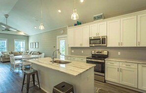 A modern kitchen with white cabinets, a central island, a microwave, and a stove.