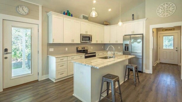 A modern kitchen with white cabinetry, a central island, stainless steel appliances, and pendant lighting. - Sea Breeze Two - Pet Friendly - New Eastpoint (Eastpoint)